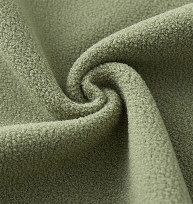 Close-up of soft green fleece fabric showing texture used in unisex sports jackets for warmth and comfort.