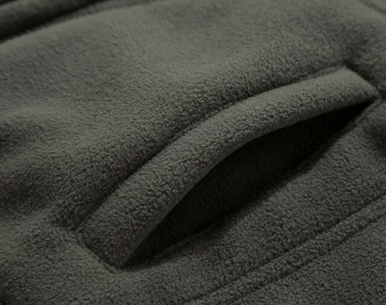 Close-up of dark green warmed solid color men's jacket pocket, showcasing soft cotton material and sleek design for casual style.