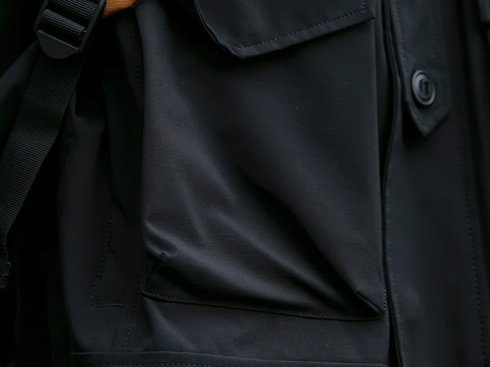 Close-up of waterproof jacket pocket showcasing durable fabric and button detail for outdoor use.