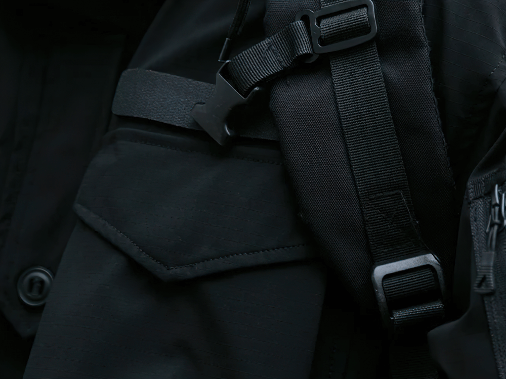 Close-up of black waterproof hooded jacket with utility pocket and strap detail, designed for extreme outdoor conditions. Model SF2262.