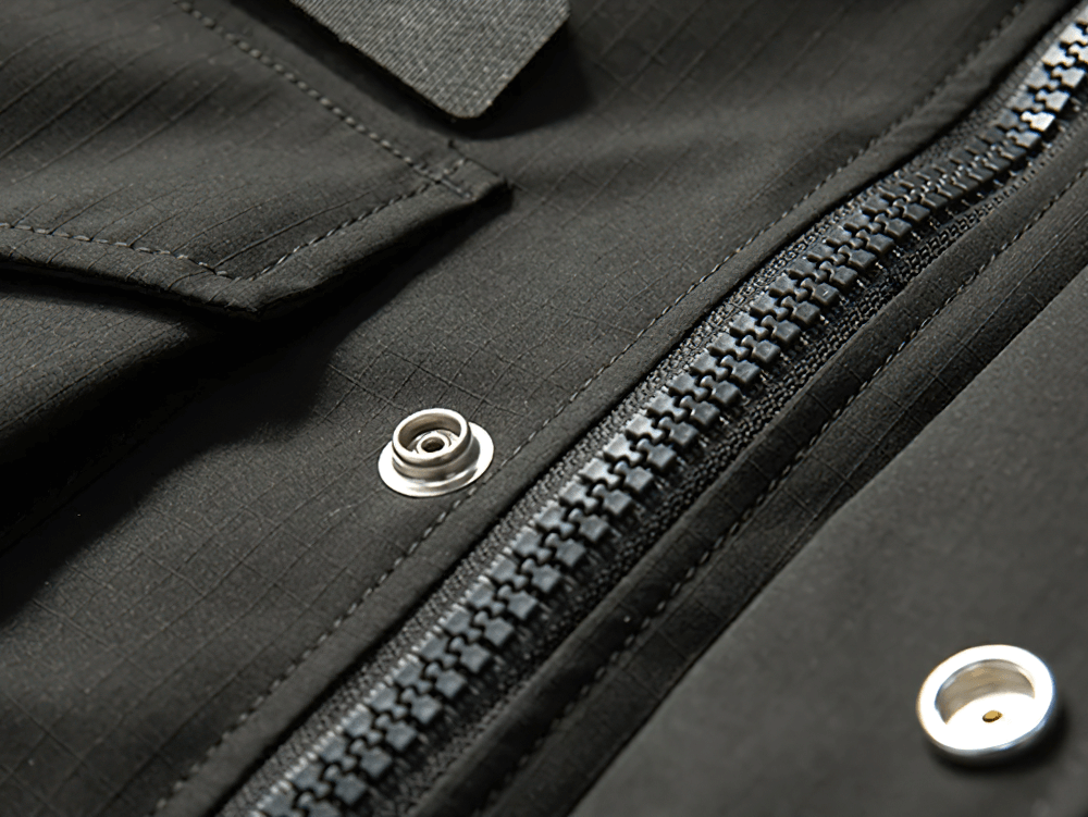 Close-up of black waterproof hooded jacket with multiple pockets and sturdy zipper, designed for extreme outdoor conditions.