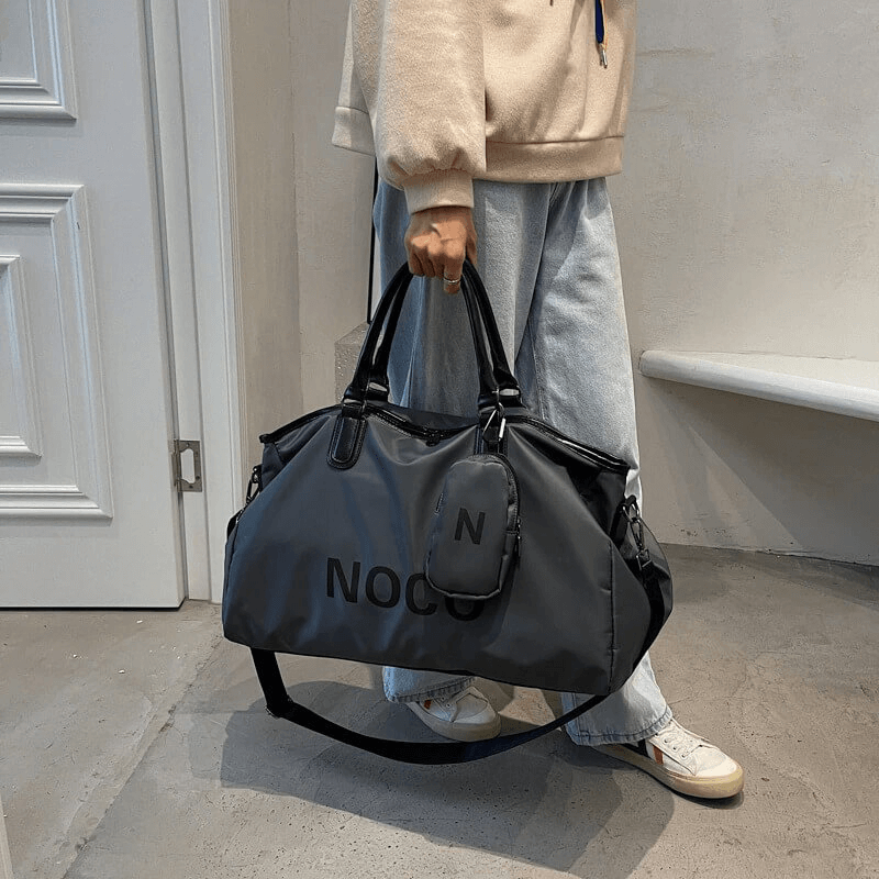 Unisex waterproof large shoulder bag in black nylon, perfect for fitness and travel. Stylish sports accessory held by person in casual attire.