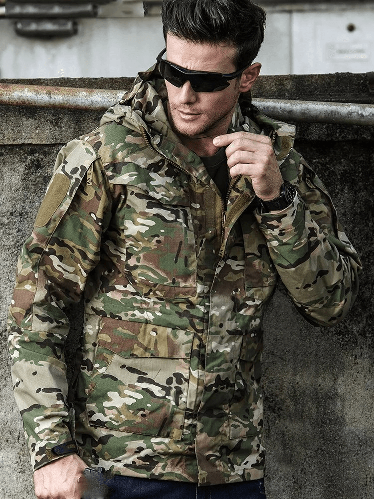 Man wearing camouflage waterproof windbreaker with hood and pockets, ideal for outdoor activities like hiking and biking.