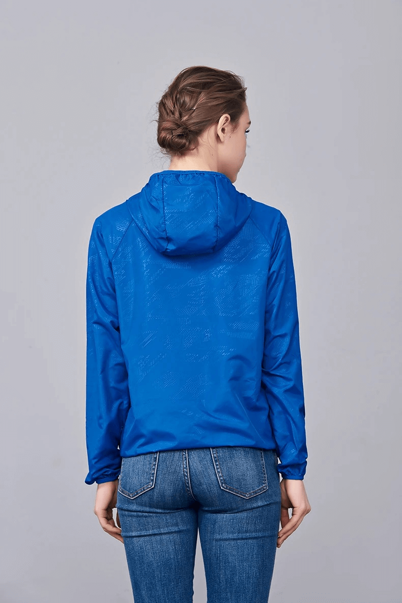 Woman wearing waterproof blue hiking jacket with hood, perfect for camping outdoors. Breathable, sun-protective, lightweight polyester.