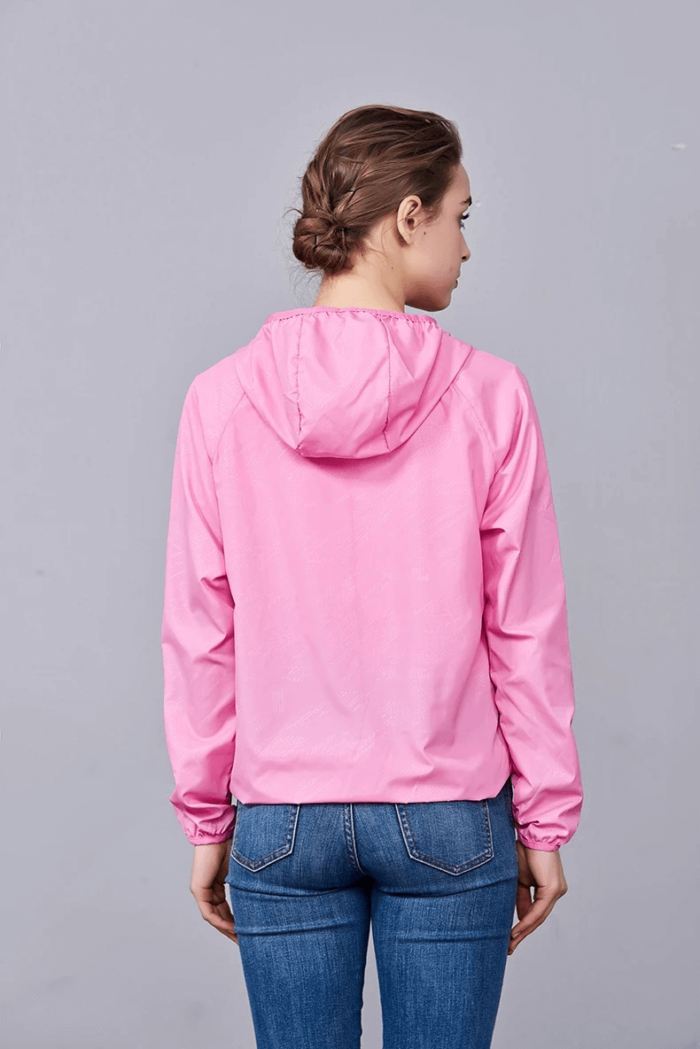 Person wearing pink waterproof polyester hiking jacket with hood, view from the back.