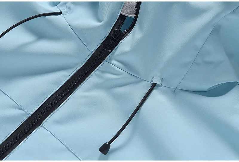 Close-up of blue waterproof ski jacket with hood, showing zipper detail. Unisex design for ultimate warmth and comfort during winter activities.