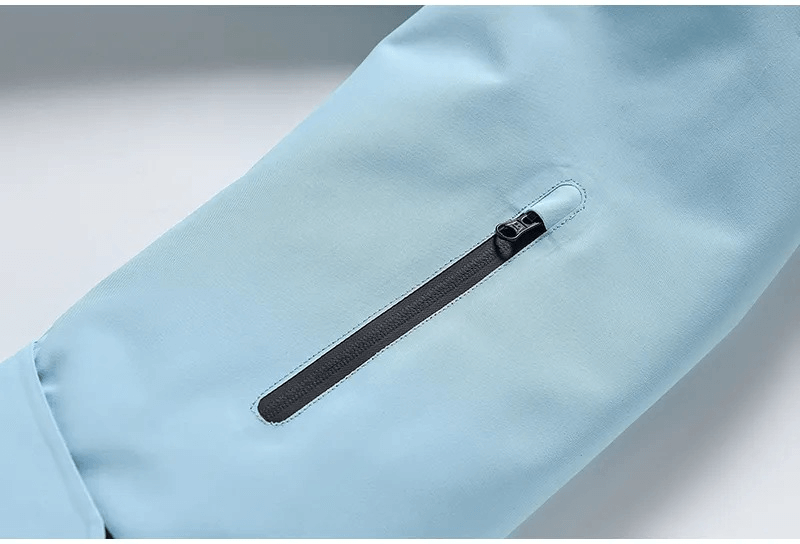 Close-up of light blue waterproof ski jacket sleeve with a zippered pocket, showcasing the durable and stylish design for winter activities.