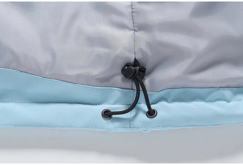 Close-up of waterproof ski jacket hem with adjustable drawstring for a snug fit, showcasing polyester fabric in gray and blue.
