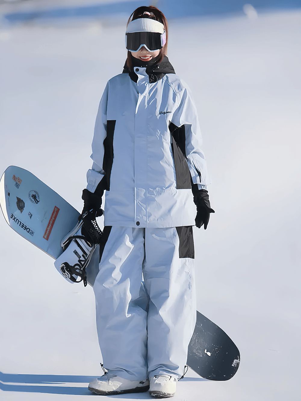 Snowboarder wearing a waterproof and windproof snowboarding jacket and pants set, holding a snowboard on snowy slopes.