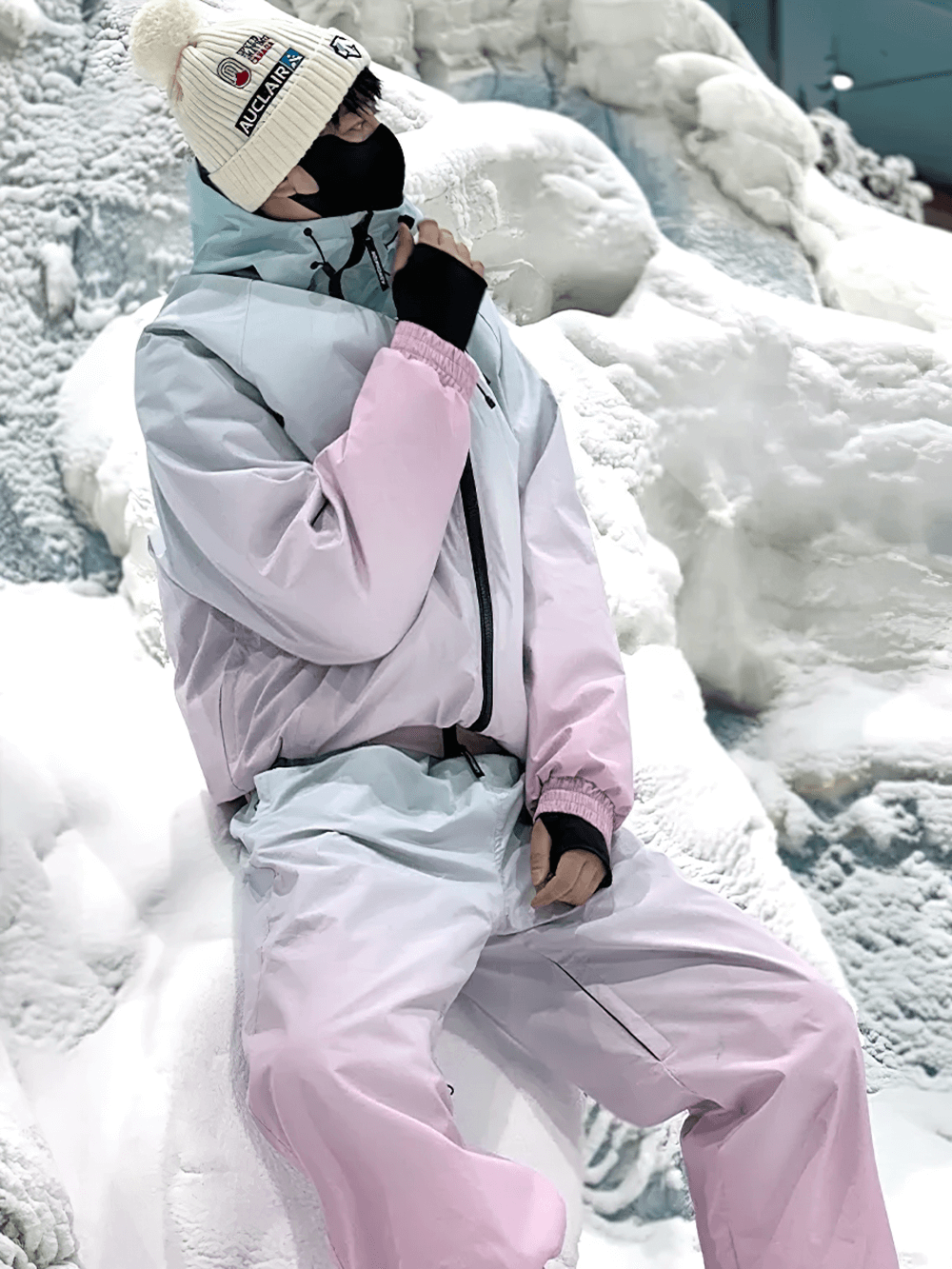 Gradient waterproof snowsuit for skiing and snowboarding, featuring pink and blue design, worn by person on snowy slope.