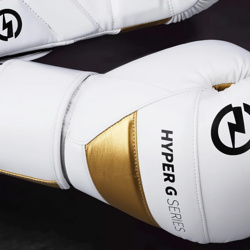 White and gold wear-resistant PU leather boxing gloves, Hyper G series, designed for sparring and combat sports with ergonomic fit.