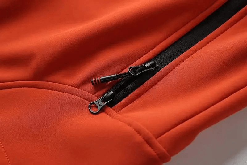 Close-up of the Weather-Resistant Softshell Hooded Jacket's zippered pocket. Ideal for outdoor activities like hiking and camping.