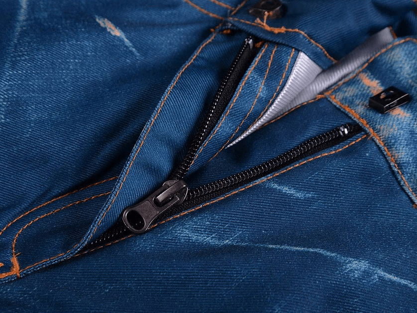 Close-up of blue denim snowboard pants with zipper fly, highlighting windproof design for skiing in cold weather.
