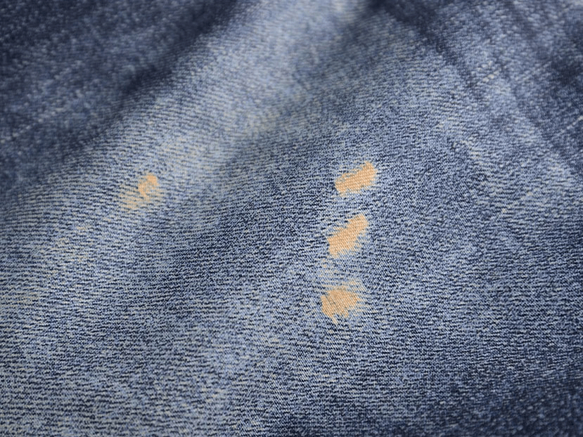 Close-up of blue denim fabric with brown stitching, showing texture and detail.