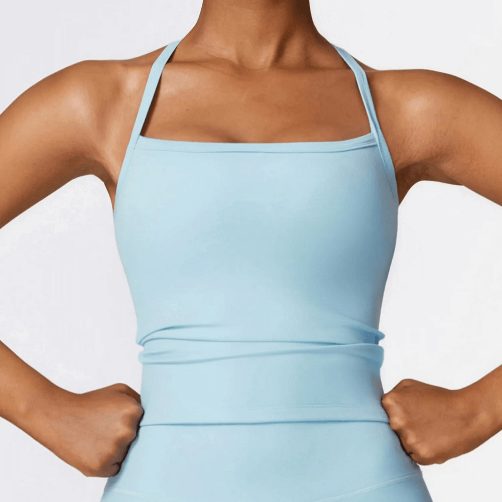 Woman wearing a light blue breathable cross-back tank top ideal for yoga and fitness sessions.