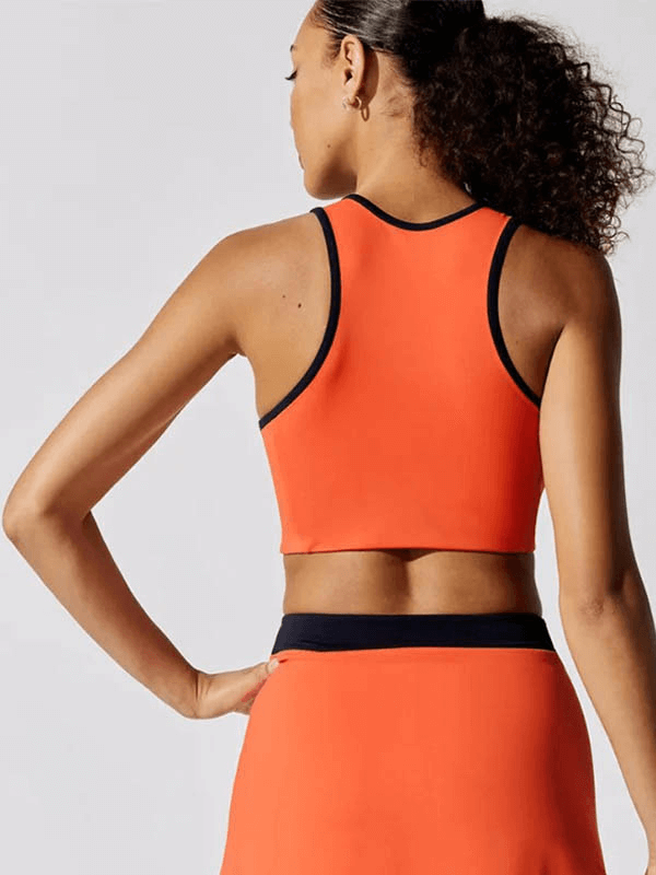 Back view of woman in orange absorbing, breathable crop tennis tank SF1800, perfect for staying cool and dry on the court.