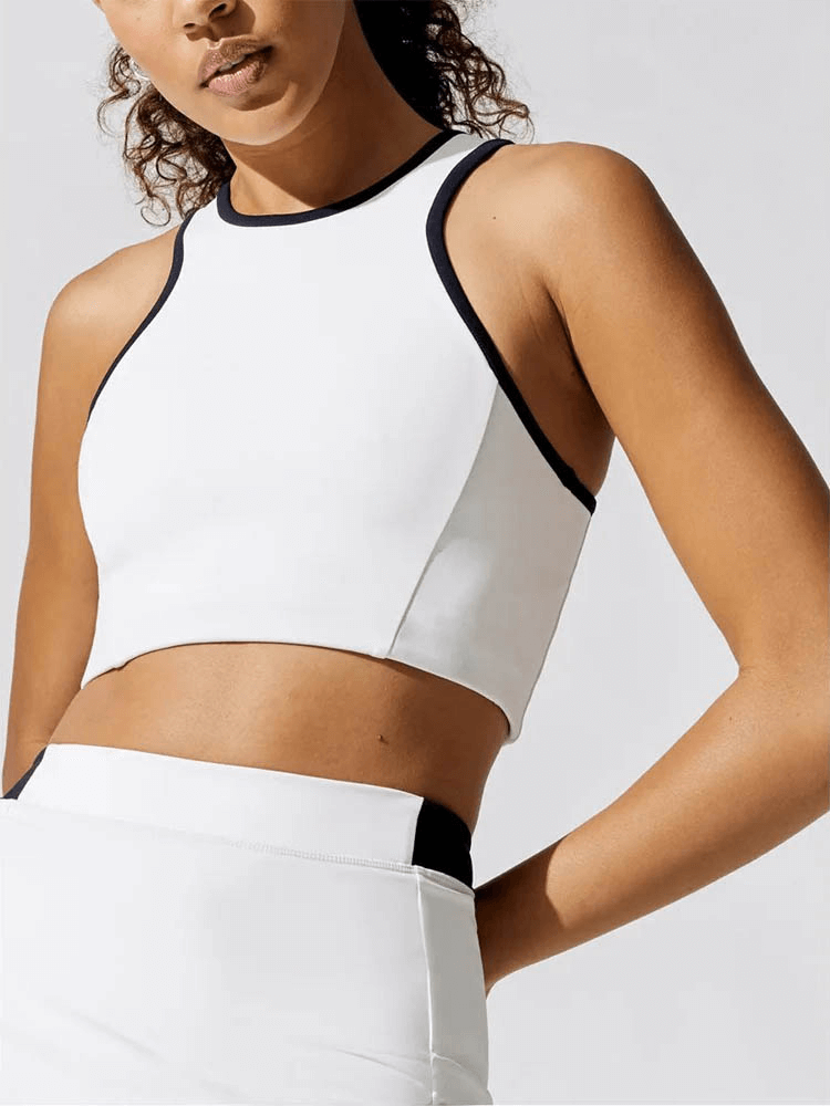 Woman wearing a breathable white crop tennis tank, made of polyester and spandex, perfect for staying cool on the court.