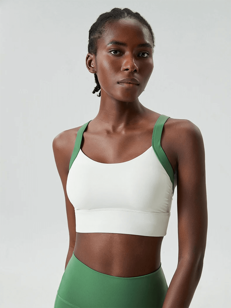 Woman wearing a white and green athletic bra top for yoga and fitness, showcasing sporty design and ultimate support.
