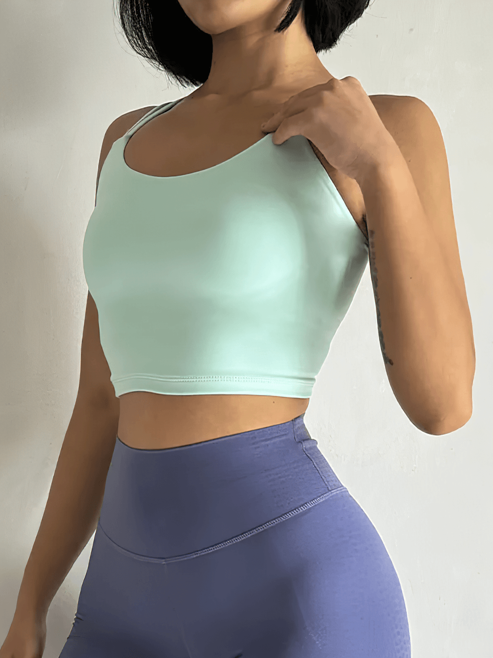 Model wearing mint green Women's Back-Knot Yoga Sports Bra with Fixed Pads - SF4061 and purple leggings