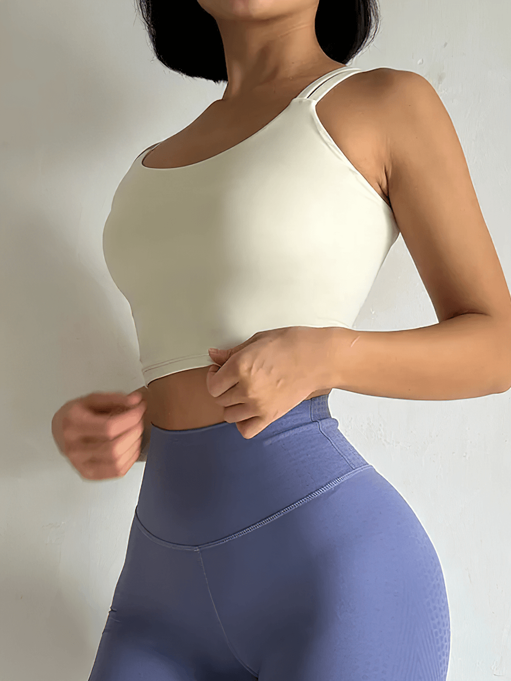 Woman wearing stylish white sports bra and purple leggings, side view