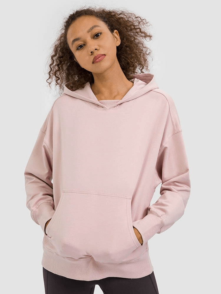 Woman wearing a pink batwing sleeves hoodie for running, hands in pockets, stylish and cozy outerwear SF0075.