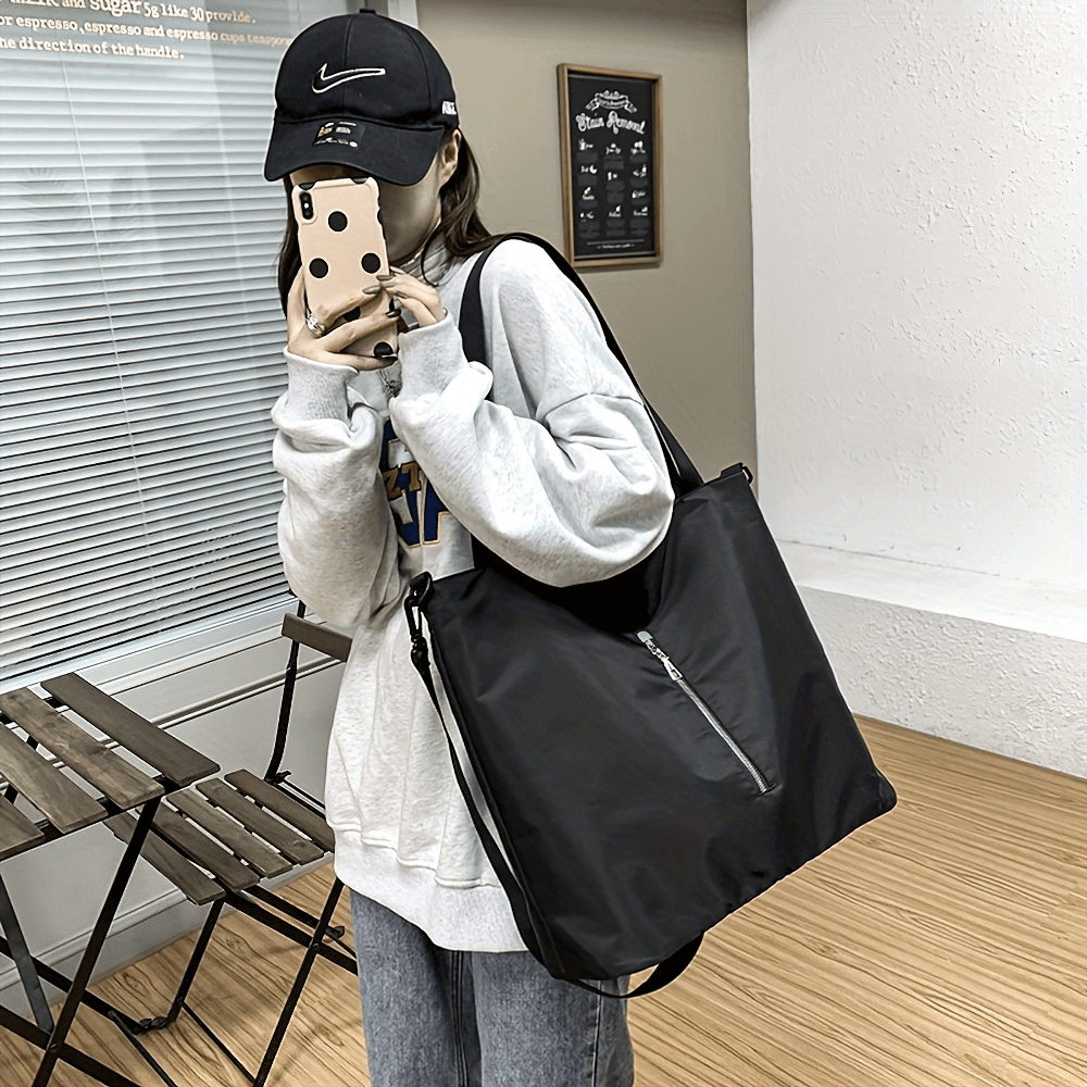 Woman holding black large capacity tote bag SF2664, sporty chic with adjustable strap and zip closure, perfect for travel and everyday use.