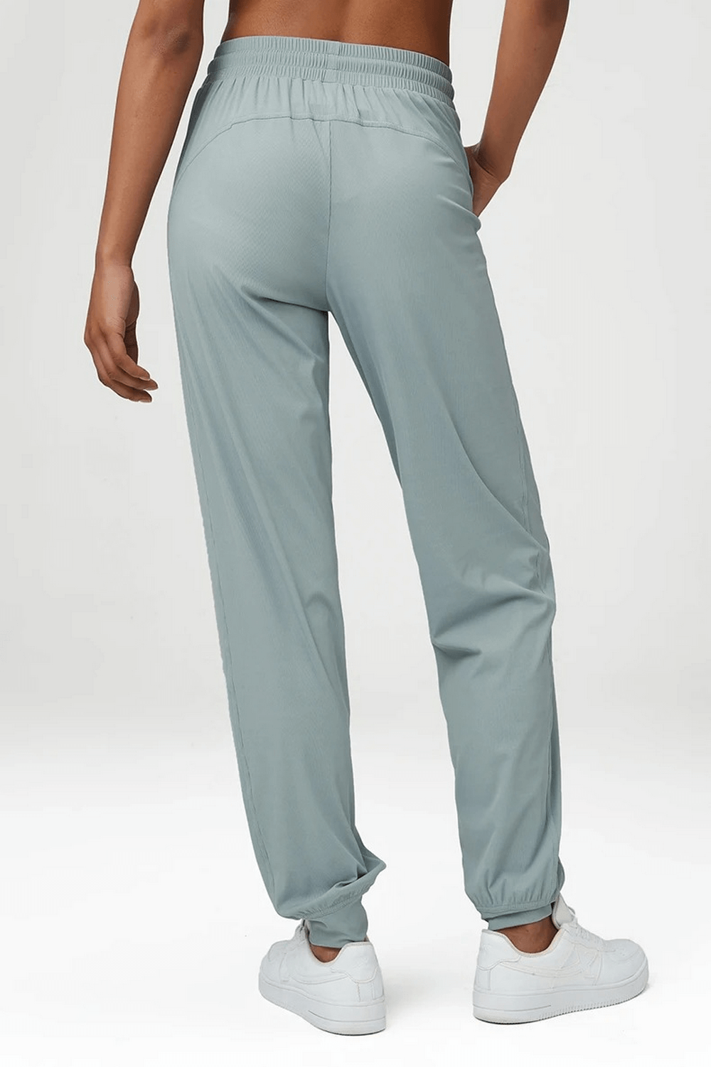 Model wearing light green women's breathable drawstring loose pants SF2098, showcasing back view with elastic waistband and cuffed ankles.