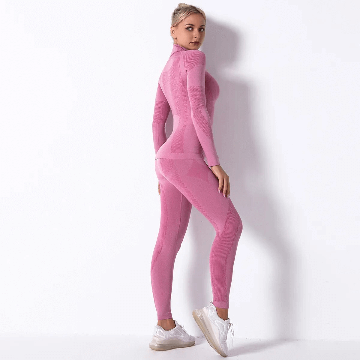 Woman in pink elastic leggings and long sleeve top set, perfect for yoga with quick-drying breathable fabric.