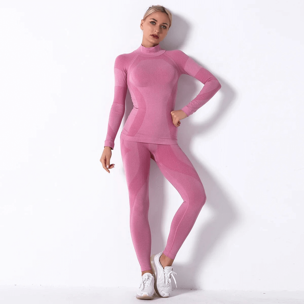 Women's pink elastic leggings and long sleeve top set for yoga, made from breathable polyester, worn by a female model.