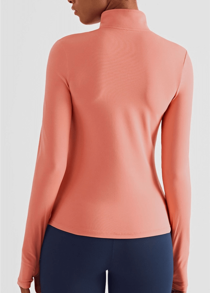 Alt Tag: Woman wearing a peach long sleeve fitness sweatshirt with finger cut-outs, showcasing a sporty and sleek design from behind.