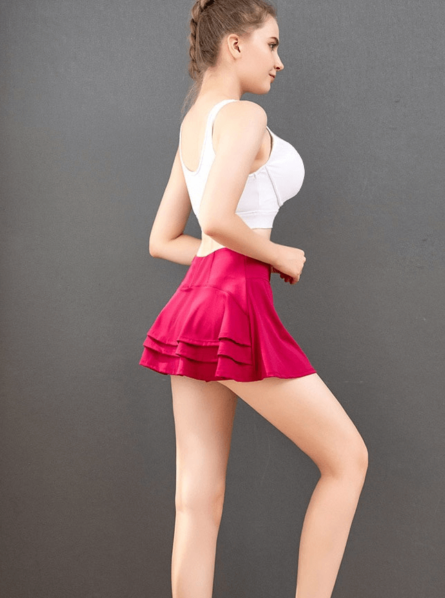 Woman wearing a pink pleated golf tennis shorts-skirt with inside pocket, showcasing sporty style and comfort.