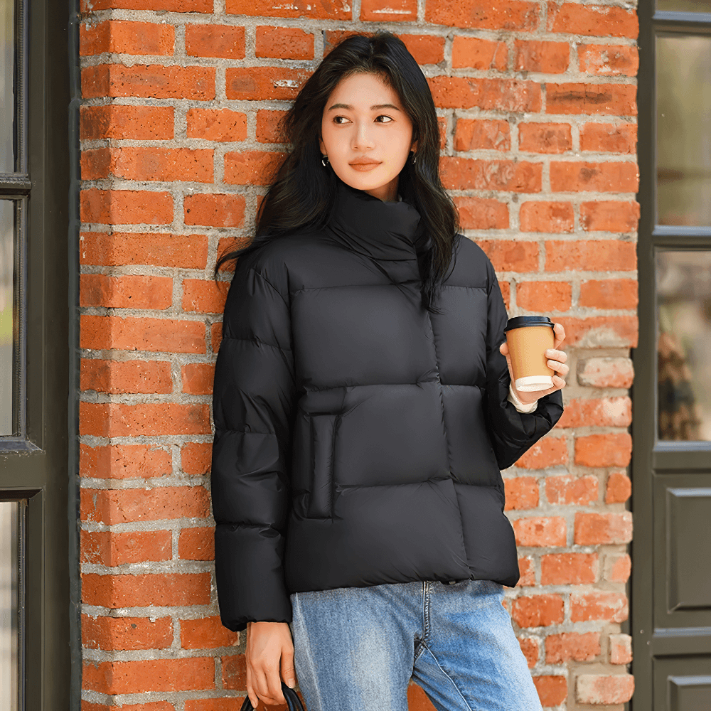 Woman wearing elegant black goose down jacket with stand-up collar and holding a coffee, perfect for casual winter elegance.