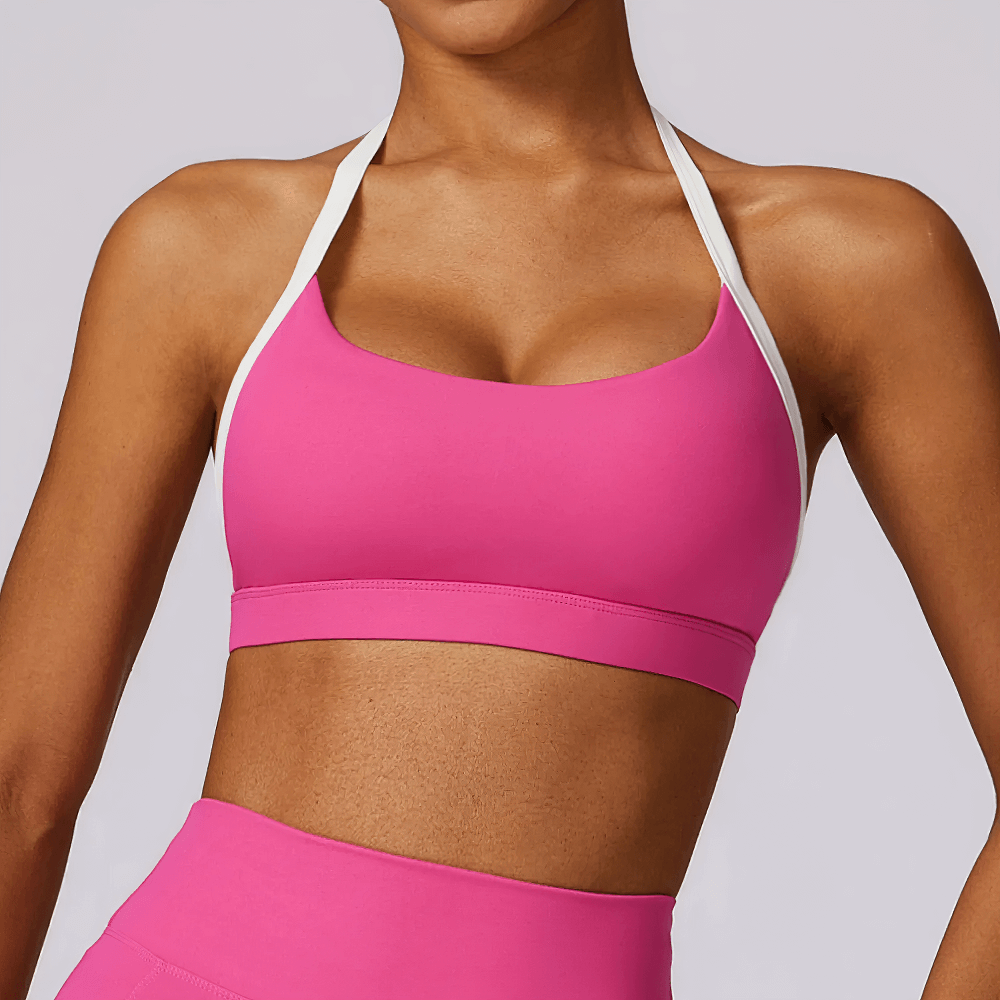 Women's pink halter sports bra with white contrast trim, designed for active workouts, providing stylish light support and breathability.