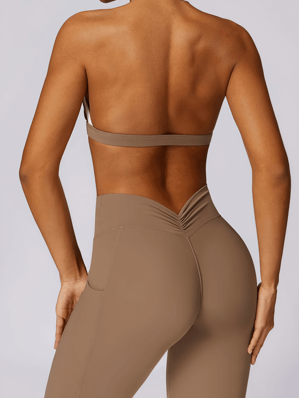 Back view of a woman wearing a halter sports bra and leggings, showcasing the open-back design and comfortable fit for activewear.