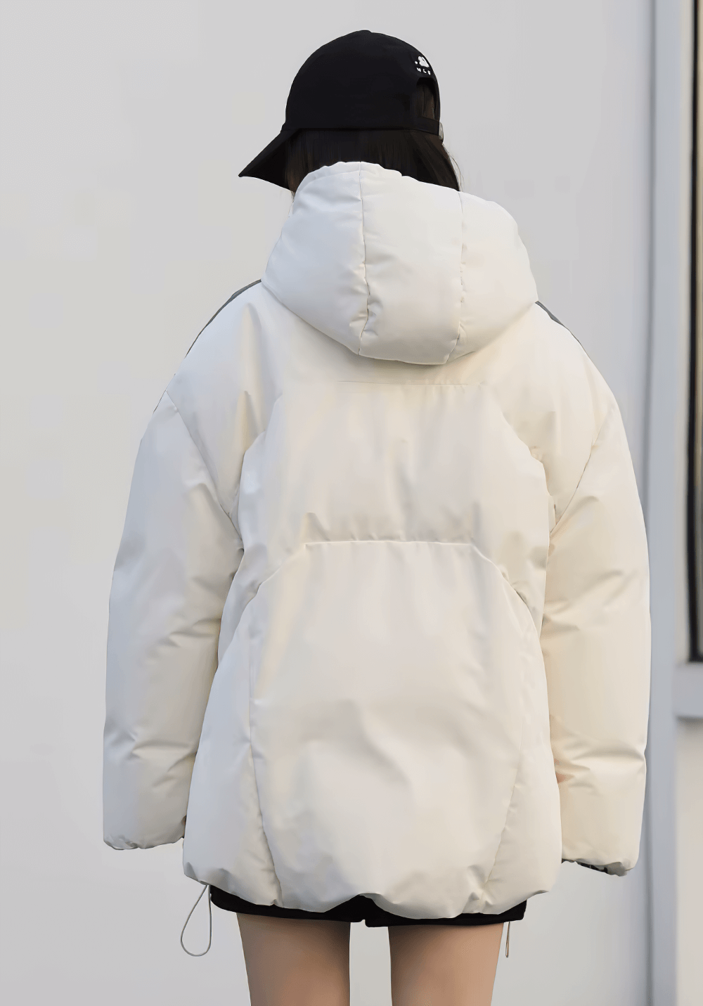 Woman wearing a hooded, white duck down winter jacket with a casual streetwear design, shown from the back for style detail.