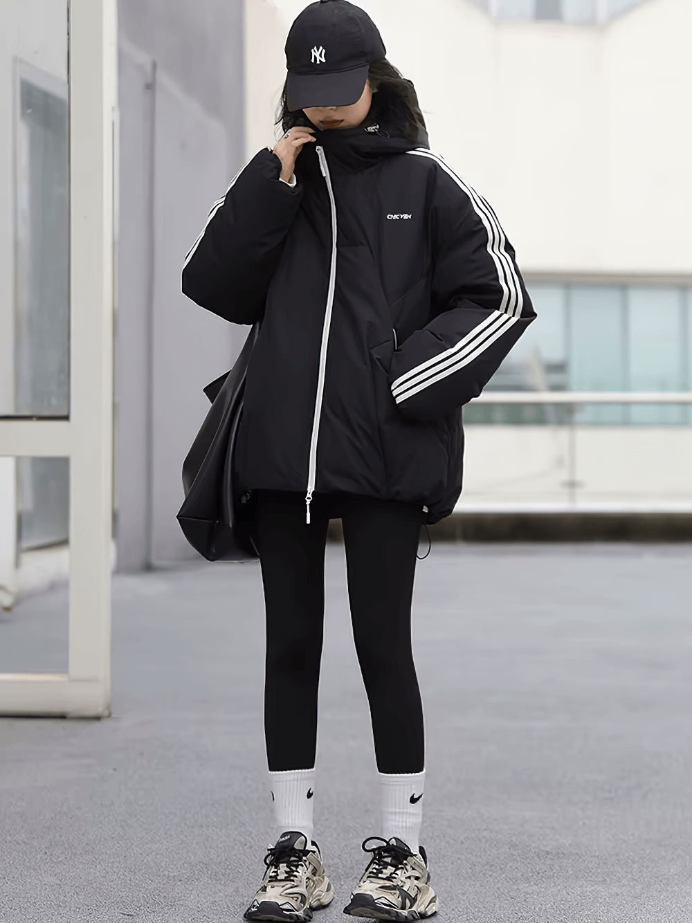 Woman wearing hooded duck down winter jacket with stripes, urban streetwear style for warmth and comfort.