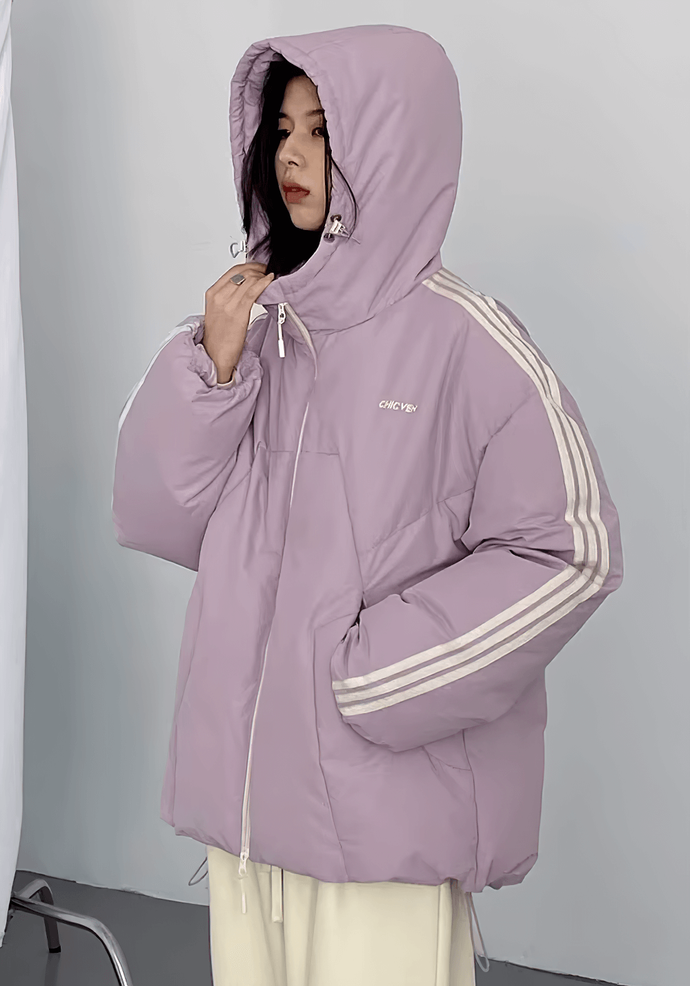 Woman wearing a purple hooded down jacket with striped sleeves, showcasing a stylish streetwear look.