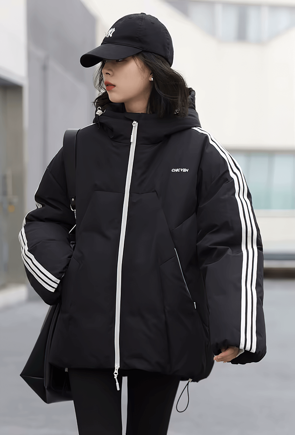 Woman in black hooded striped down winter jacket looking stylish and warm, streetwear casual fashion vibe.