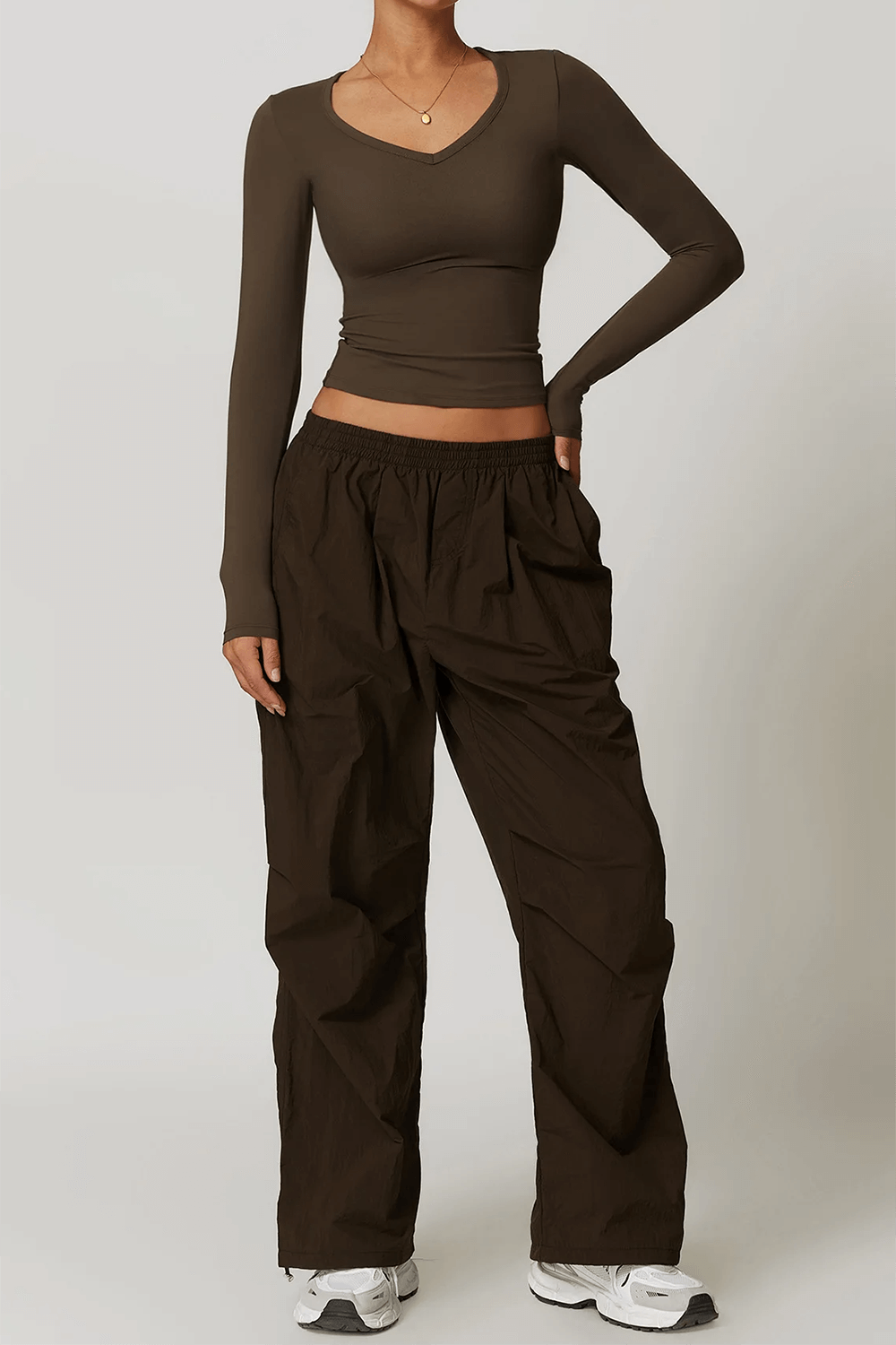 Model wearing brown long-sleeved yoga crop top with loose pants and sneakers.