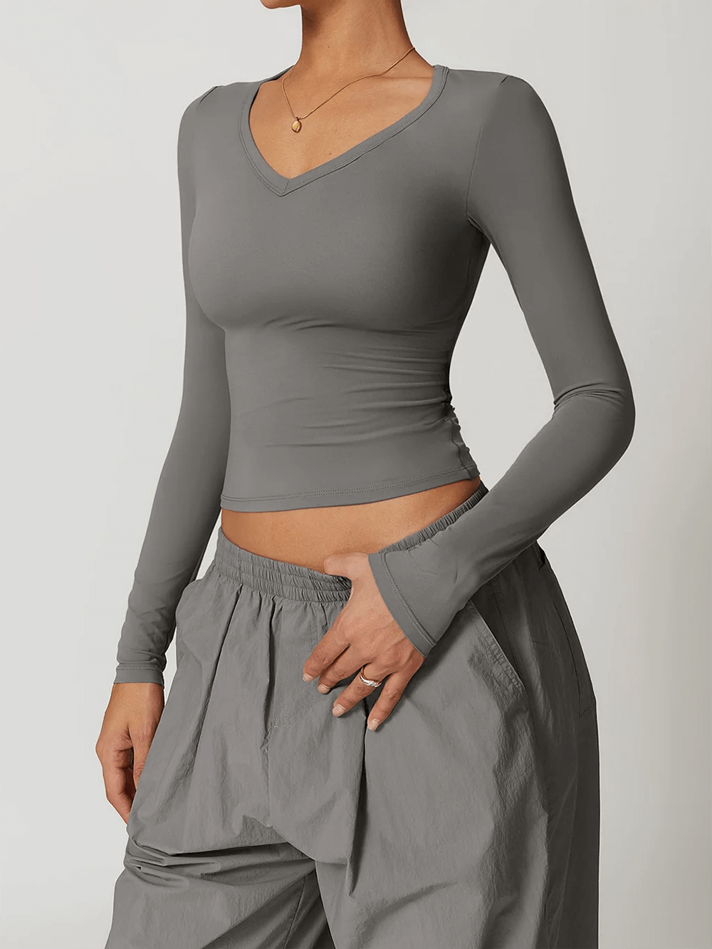 Woman in gray long-sleeve yoga crop top, perfect for workouts with quick-dry, stretchy fabric, demonstrating sleek fit.