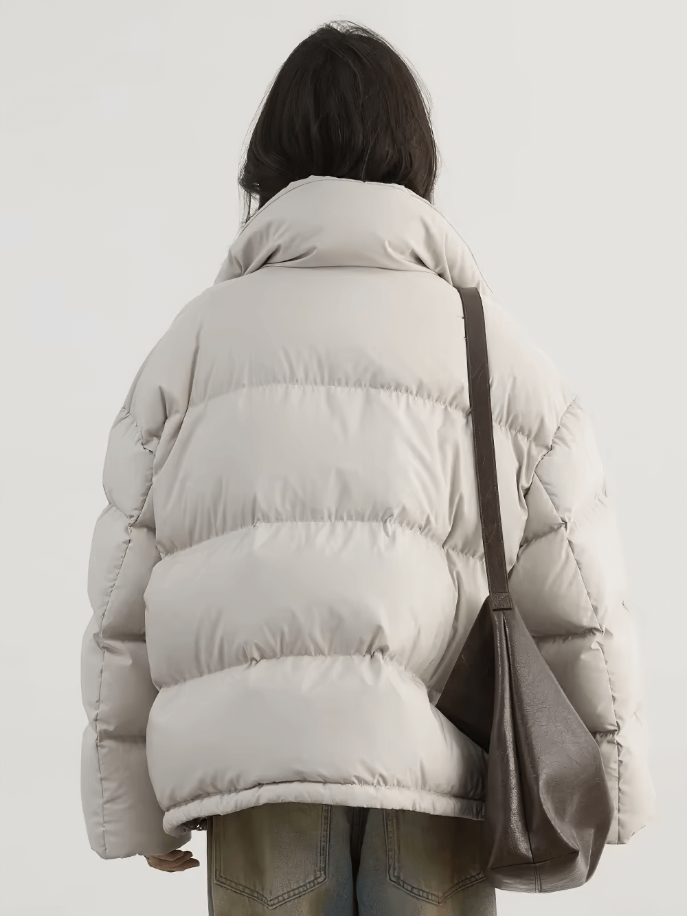 Woman wearing a white duck down stand collar winter jacket with a puff design, shown from the back, paired with a dark shoulder bag.