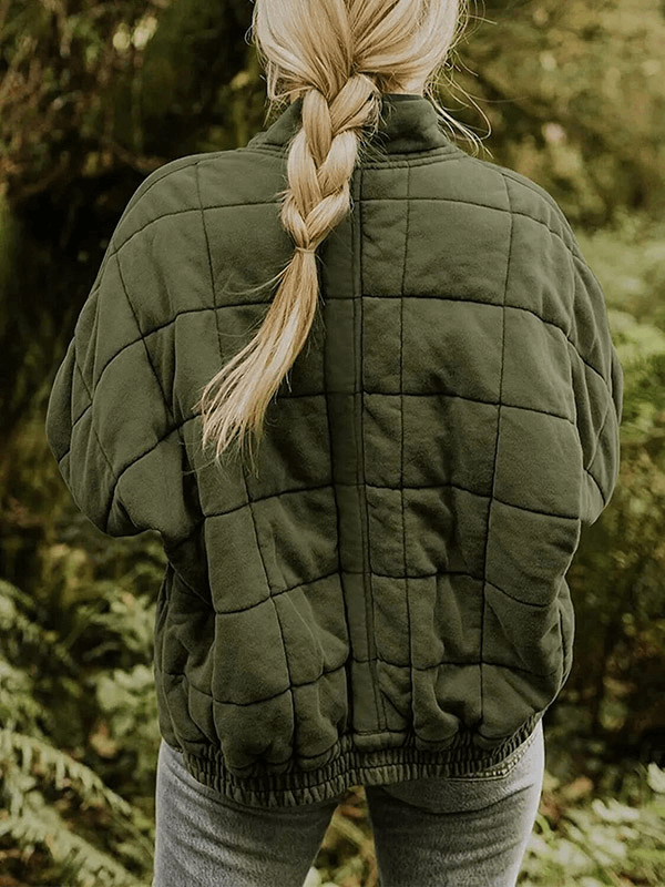 Back view of woman in green quilted stand collar jacket with zipper, standing in a forest, showcasing warmth and cozy winter style.