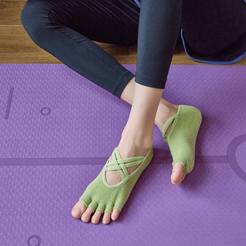 Green non-slip five-toe yoga bandage socks for women on purple mat, perfect for comfort and grip during yoga practice.
