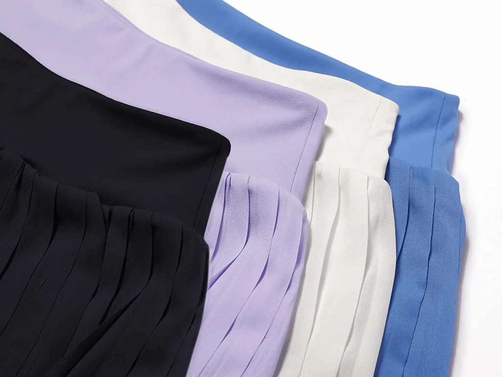 Colorful pleated tennis skirts in black, purple, white, and blue, perfect for athletic style and performance on the court.