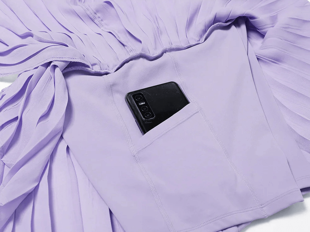Lilac pleated skort with built-in pocket holding a smartphone, showcasing practical design and functionality for active wear.