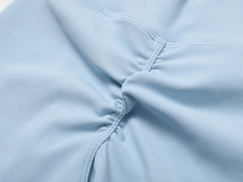 Close-up of light blue ribbed cross leggings with detailed stitching, highlighting the breathable and anti-shrink nylon-spandex fabric.