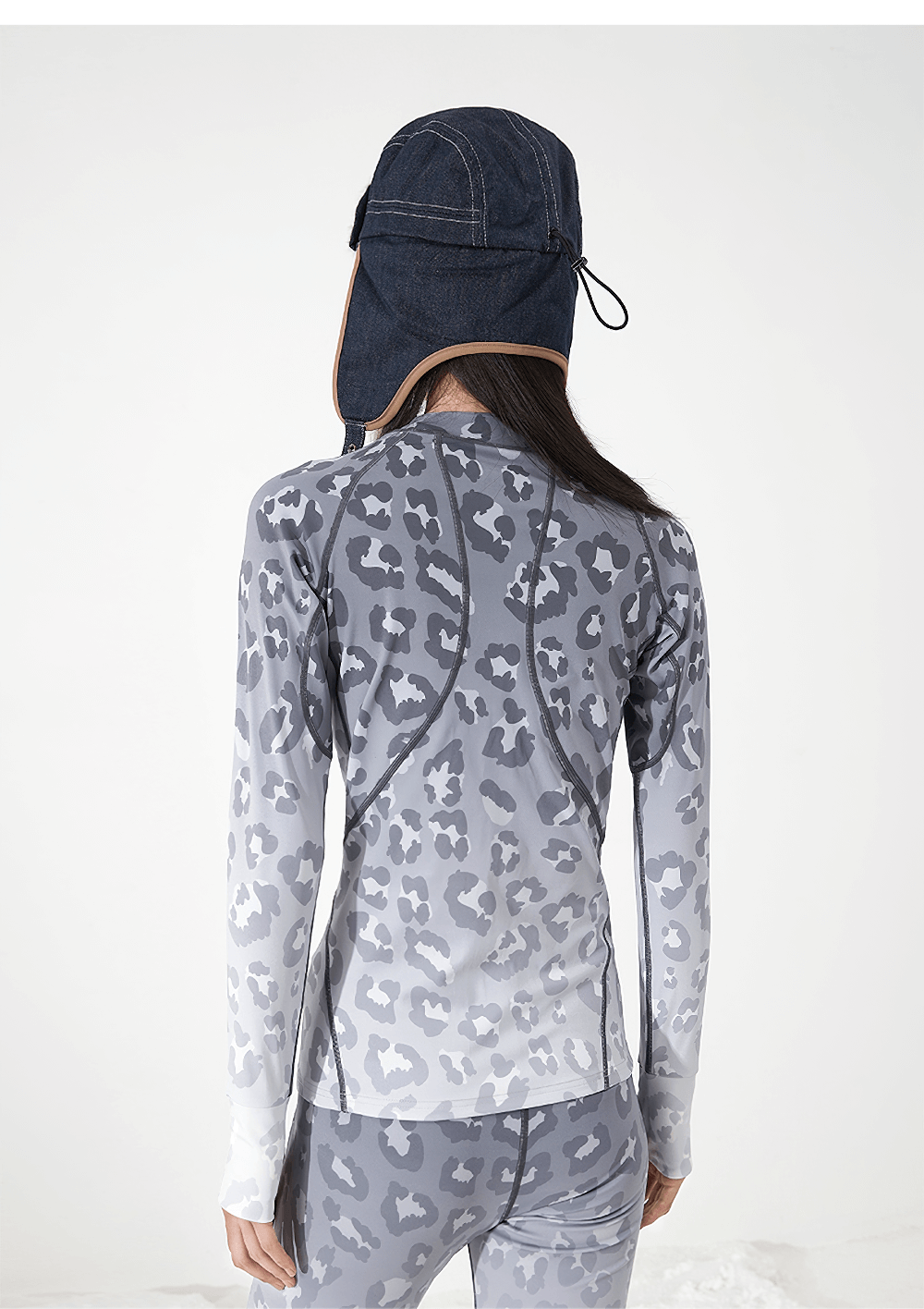 Woman in winter hat wearing a grey patterned thermal base layer set, viewed from the back, perfect for skiing and yoga.