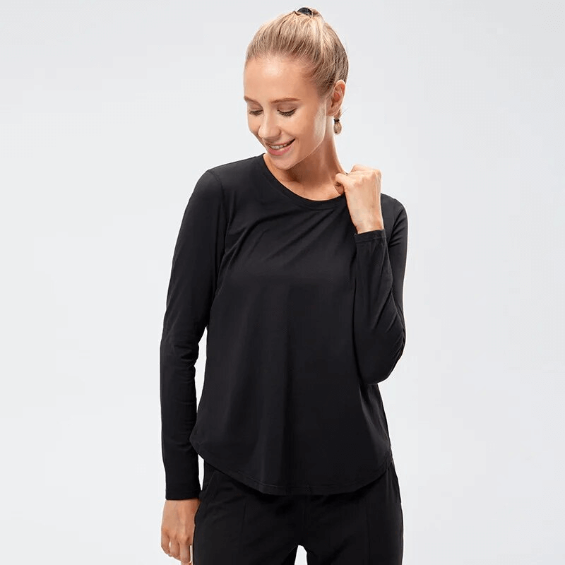 Woman wearing black quick-drying long-sleeve sports top for yoga, showcasing loose fit and comfort. Perfect activewear choice.