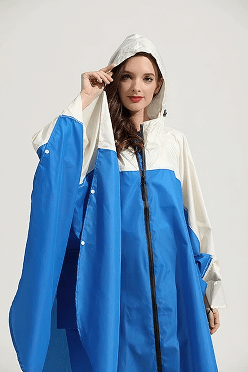 Woman wearing blue and white raincoat poncho with hood and zipper, showcasing waterproof polyester design. Perfect for rainy days.