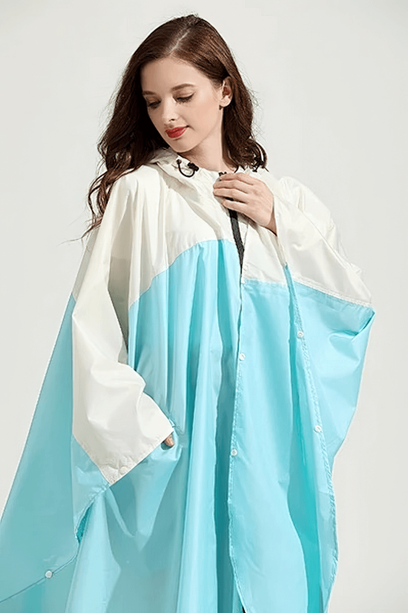 Woman wearing stylish blue and white raincoat-poncho with zipper and hood, perfect for protection on rainy days.